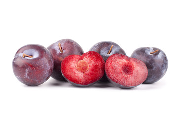 Four whole plums and one plum cut in half red color with bone inside on white background isolated close up