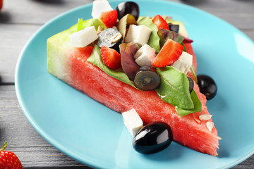 Plate with slice of watermelon and tasty salad on wooden table, closeup