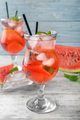 Glass of tasty cold watermelon lemonade on light wooden table