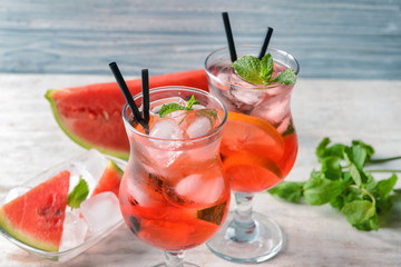 Glasses of tasty cold watermelon lemonade on light wooden table