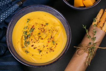 Pumpkin soup in blue bowl topped with fresh herb