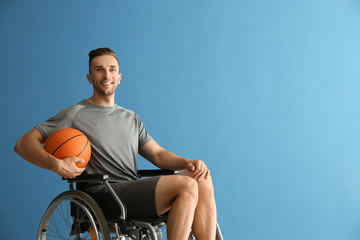 Obraz premium Young basketball player sitting in wheelchair against color background