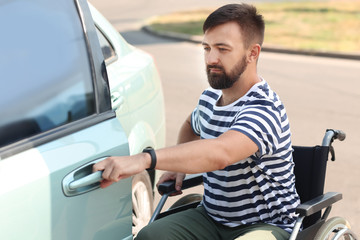 Man in wheelchair trying to sit in his car