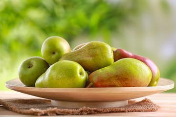 Plate with ripe pears on table against blurred background
