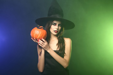 Beautiful woman dressed as witch for Halloween on color background