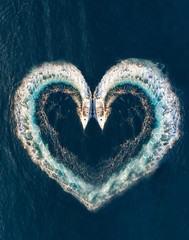 Zwei Motorboote zeichnen ein Herz aus Luftblasen auf dem Meer; Luftaufnahme