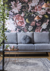 Flower print and grey sofa with a pillow in a glamour living room interior. Real photo