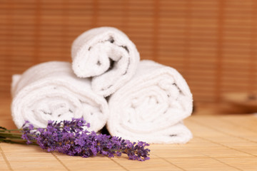 Obraz na płótnie Canvas White towels and massage rocks in spa salon over dark and light bamboo background