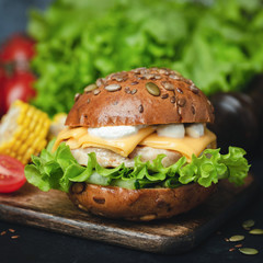 Chicken Cheeseburger with green salad and sauce. Closeup view. Tasty Cheeseburger