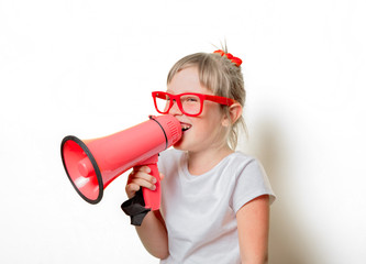 Fototapeta premium Portrait of an emotional toddler girl in glasses with megaphone on white background