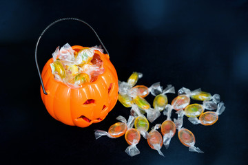 halloween Jack o Lantern candy collector full of candy and some scattered sweets on the black...