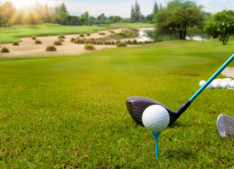 White Golf ball on tee ready to be shot on blurred beautiful landscape of golf course in bright day time with copy space. Sport, Recreation, Relax in holiday concept.