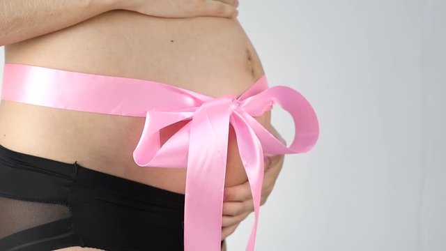 Pregnant woman with a pink ribbon on her belly. slow motion