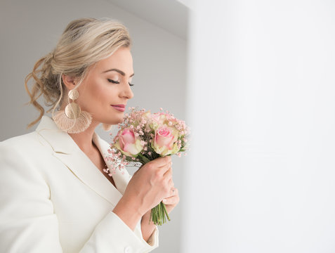 Sensual adult bride smelling bouquet