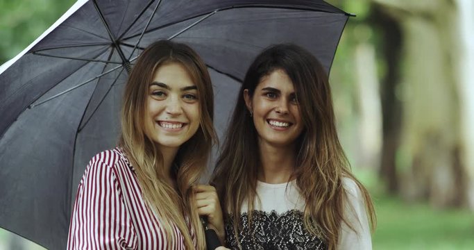 Awesome young women smiling nice looking to the camera , under the umbrella. 4k