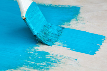 brush with turquoise paint close-up on a painted surface background