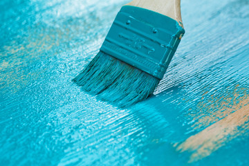 brush with turquoise paint close-up on a painted surface background