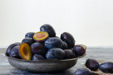 Damson plums are in the ancient copper cup.