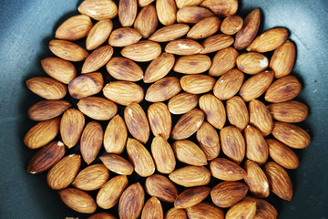 Roasted salted almond nuts in a pan, top view of a healthy vegetarian food
