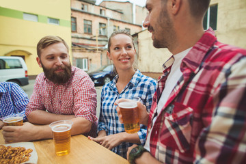 The group of friends enjoying and drinking beer at outdoor bar or pub. Boiled white sausages, served with beer and pretzels. Perfect for Octoberfest. Natural wooden background. Front view with female