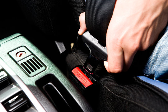 Crop shot of driver fastening seat belt