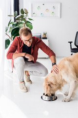 man feeding and stroking golden retriever dog