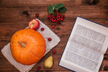Top view of autumn workplace, pumpkin, apples and book on wooden table.