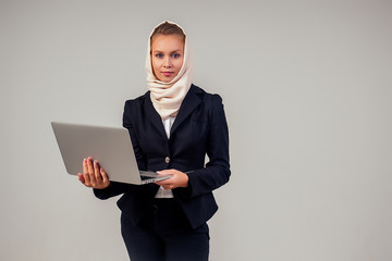 muslim business woman holding a laptop in a stylish black a jacket suit in the studio on a white background