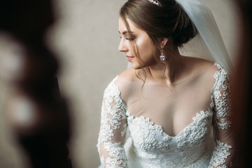 Cute bride dressed at home in a wedding dress