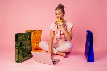 beautiful smiling blonde woman shopaholic bag and credit card in her hand sitting on floor with...