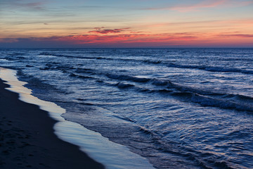 Naklejka na ściany i meble Beautiful dramatic sunset seascape with blue water and red sky.