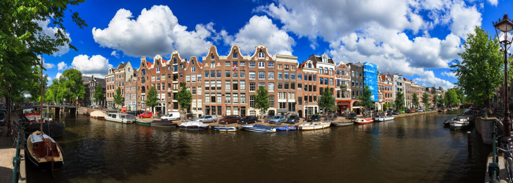 Beautiful panoramic linear panorama of the UNESCO world heritage Prinsengracht canal in Amsterdam, the Netherlands, on a sunny summer day with a blue sky and clouds
