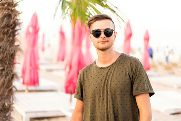 fashion guy on the beach walking in sunglasses