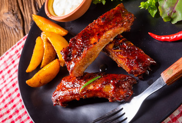 bbq spareribs on the plate with green salad and white sauce.