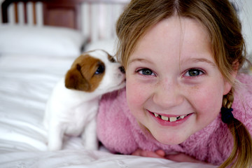 Little girl and her cute puppy on a white bed