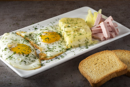Fried eggs with melted Romanian cheese called cas and some parizer
