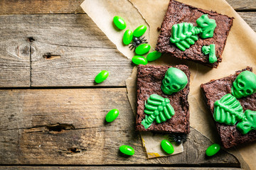 Halloween style party sweet - brownie with green skeleton and bones, rustic background