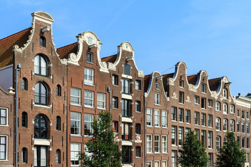 Fototapeta premium Piękny widok na domy nad kanałem Prinsengracht w Amsterdamie w Holandii w letni dzień z błękitnym niebem