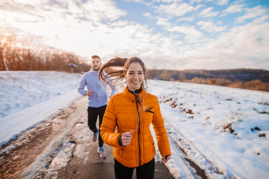 Fitness Couple Winter Morning Exercise At Snowy Mountain.