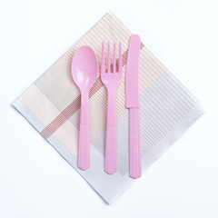 Pink color plastic fork, spoon and knife on napkin ready for kid party