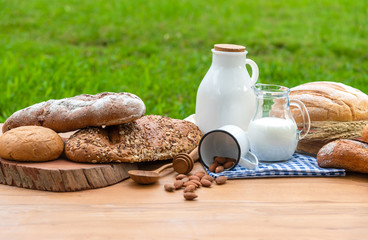 Front view of bread bun, milk, almonds and fresh milk on wooden table. Breakfast preparation, daily product.
