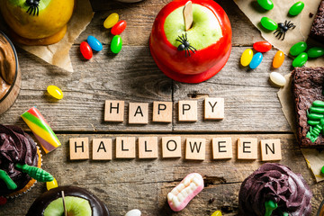 Selection of halloween party sweets - brownie, caramel apples, cupcakes, chocolate mousse, candies,...