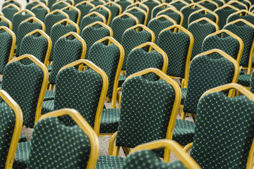 Empty chairs pattern/Rows of empty green plush chairs seen at an angle before an event.