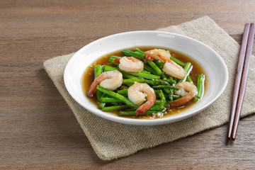 stir fried asparagus and shrimp with oyster sauce in a ceramic dish on wooden table. asian homemade style food concept.
