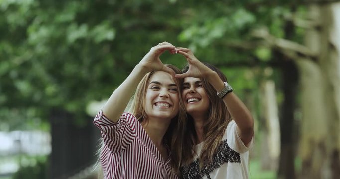 Friendship between two ladies in the parc making a heart from hands. 4k