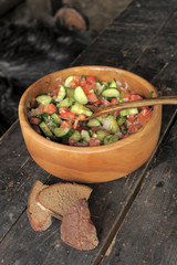 A wooden bowl with a salad and two pieces of bread