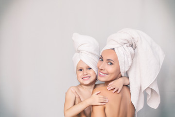 Woman young adult with daughter after shower in fresh towels hugging on isolated background