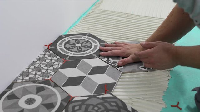 tiler laying hexagon floor tiles in home bathroom