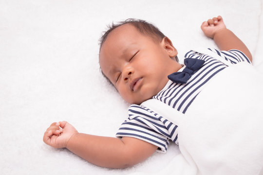 newborn asian boy baby sleeping on white furry