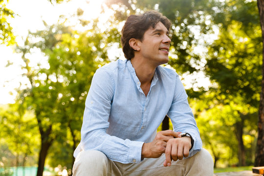 Smiling young casual man adjusting his smart watch - Powered by Adobe